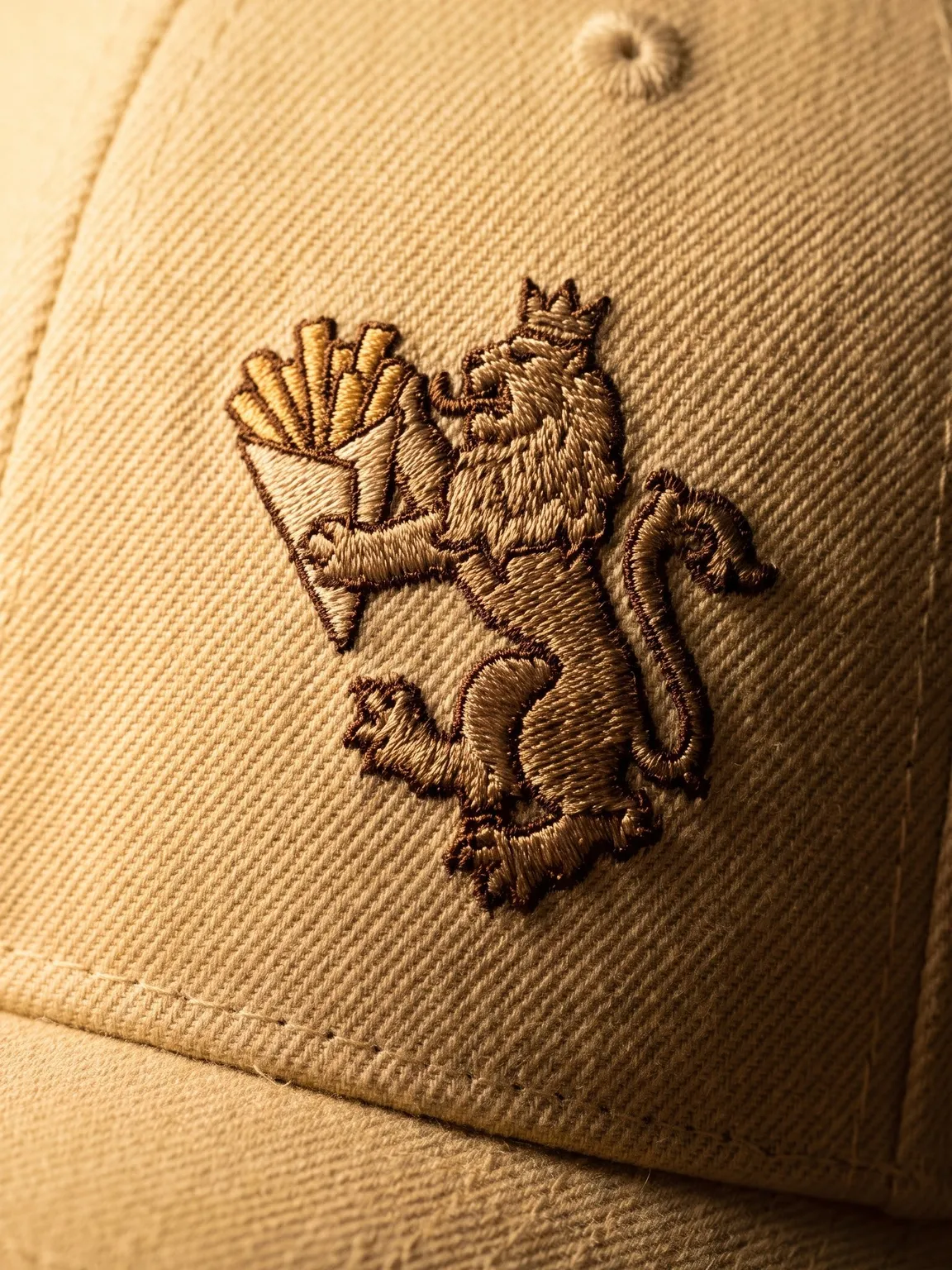 Crowned lion and fry-cone crest embroidered on a cream Friteur cap