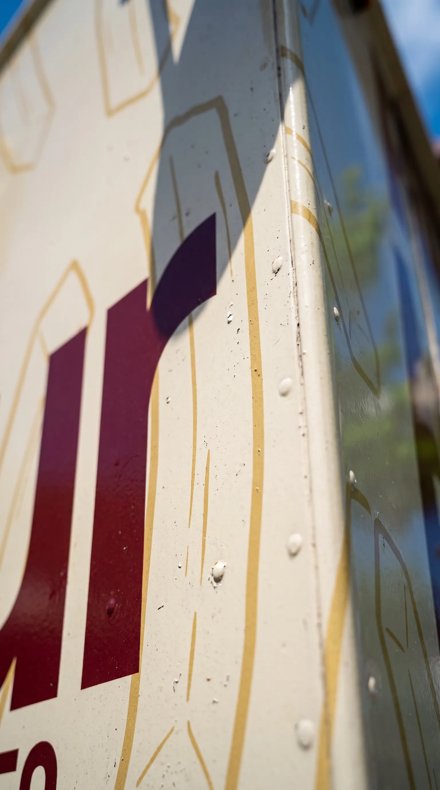 Painted corner of the Friteur truck with fry outlines and burgundy lettering in raking light