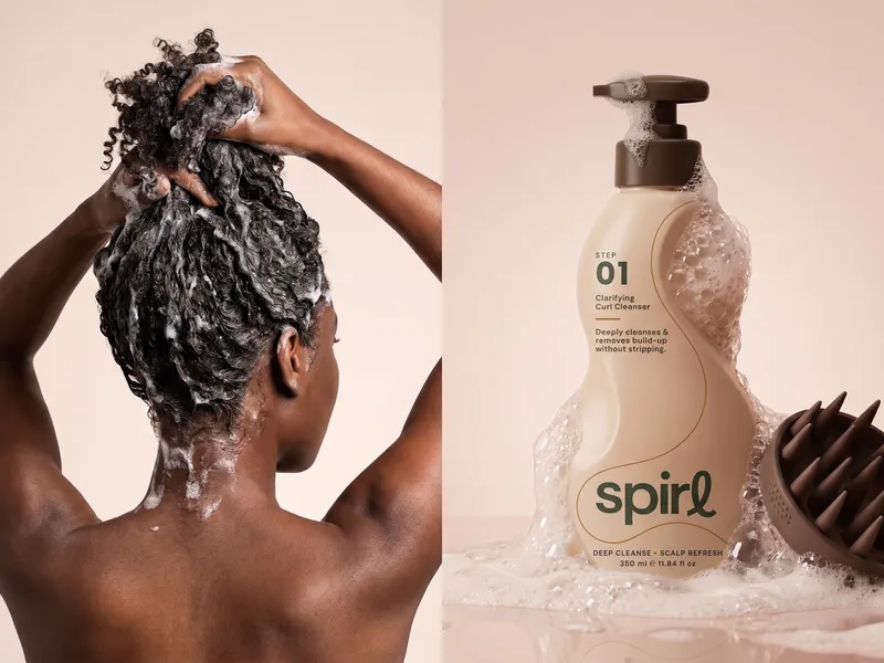 Woman lathering her curls beside the Spirl Step 01 Clarifying Curl Cleanser bottle