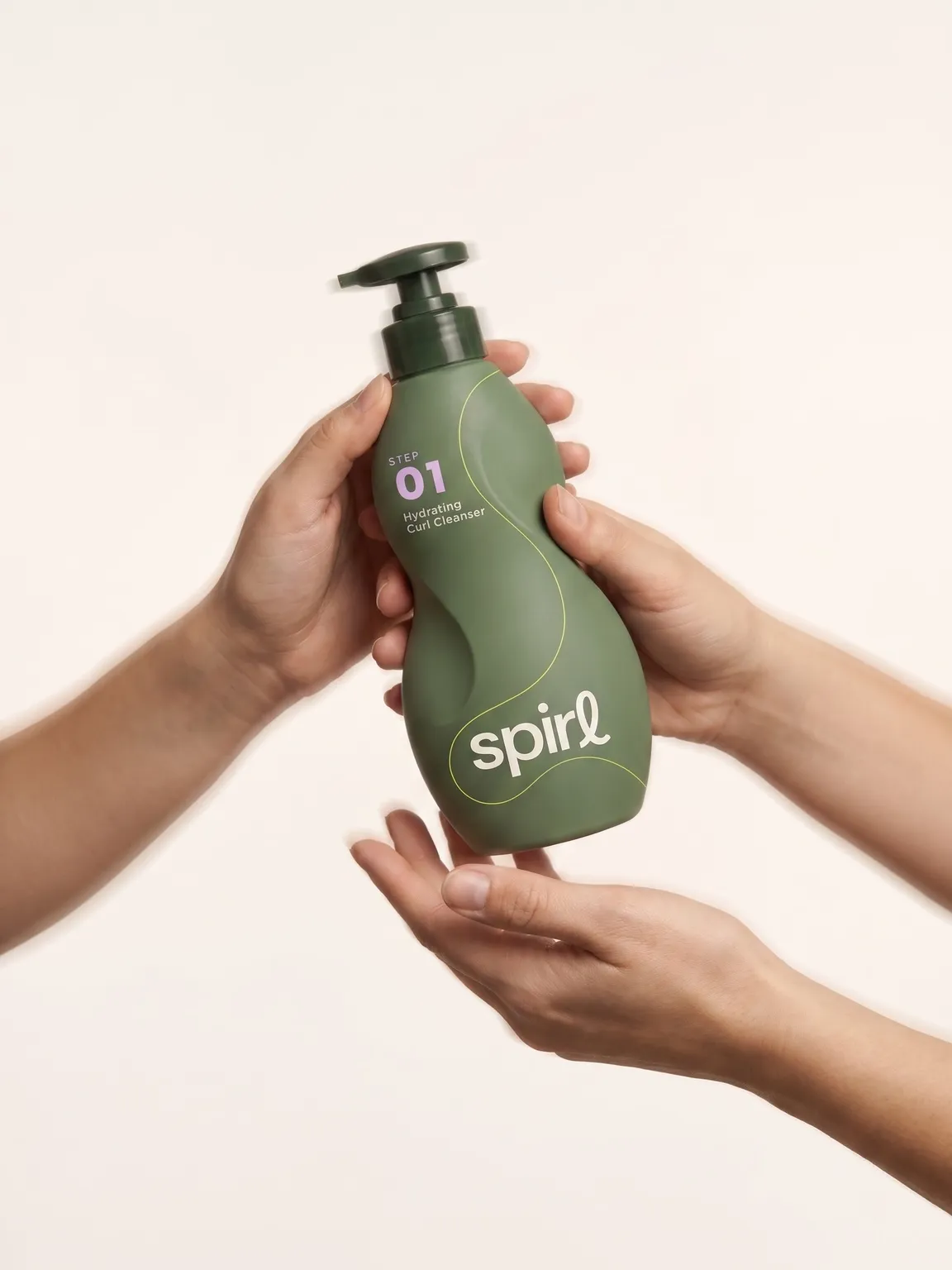 Two pairs of hands passing the sculpted green Step 01 Hydrating Curl Cleanser bottle