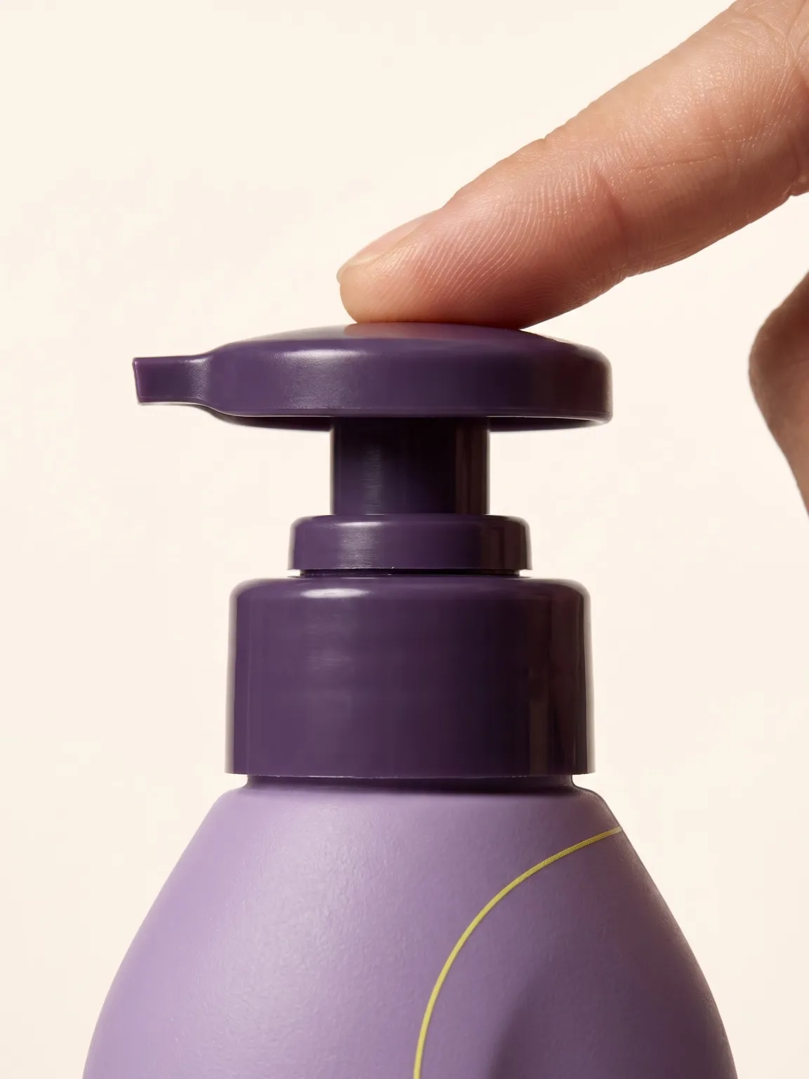 Fingertip pressing the deep-purple pump of the lilac Spirl shampoo bottle