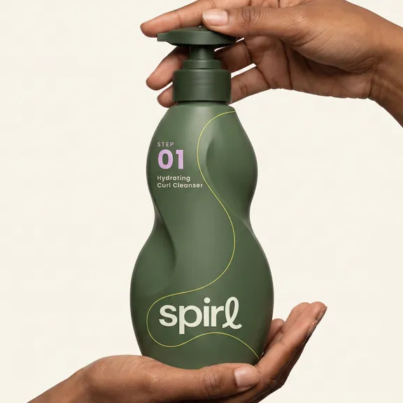 Hands pumping the green Step 01 Hydrating Curl Cleanser bottle