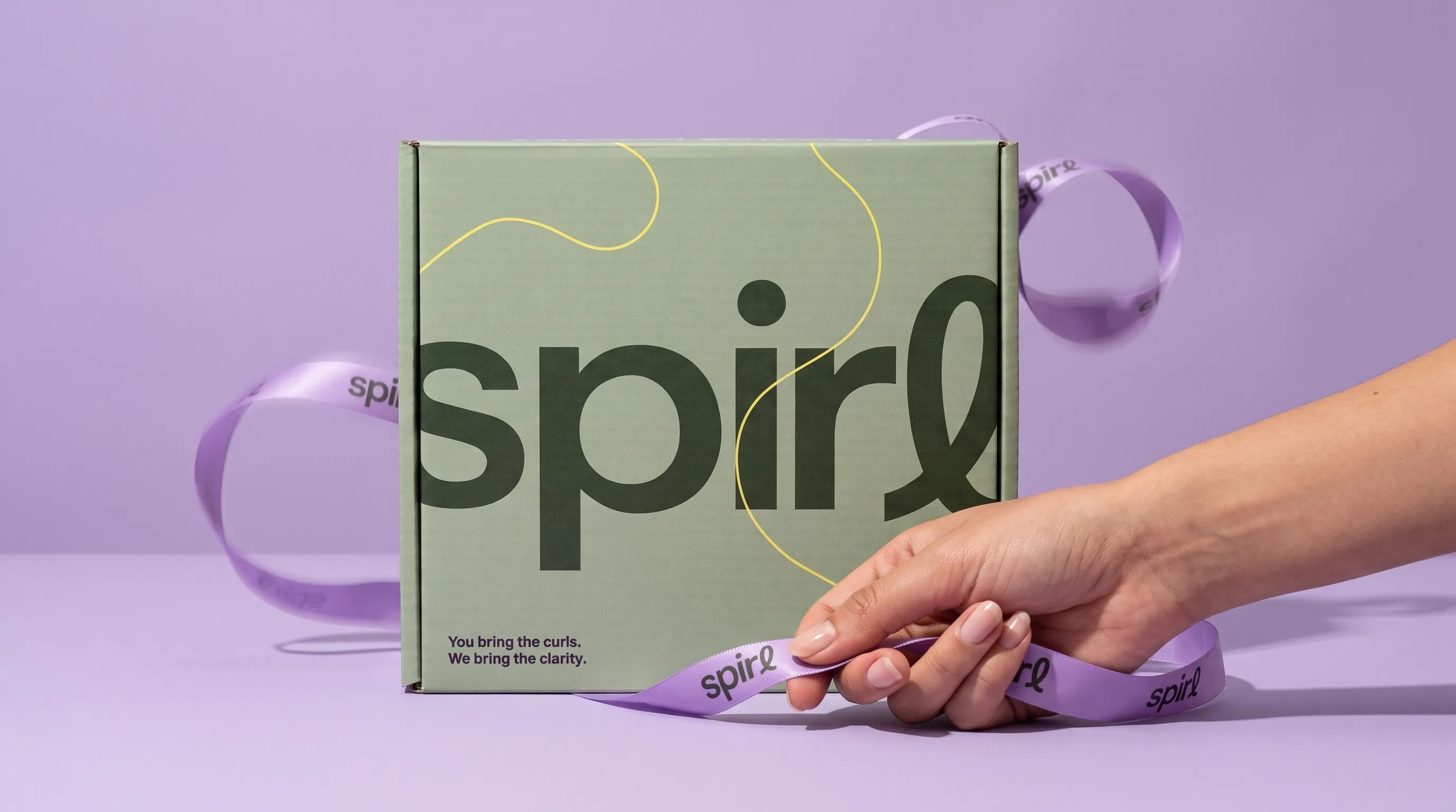 Spirl shipper box with lilac ribbon: "You bring the curls. We bring the clarity."